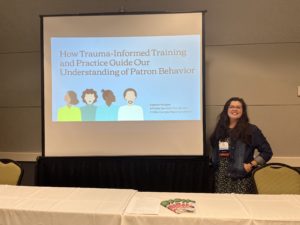 woman smiling next to presentation about trauma-informed training